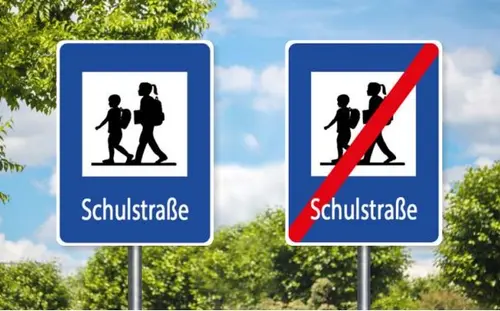 Verkehrstafel Schulstraße: eckig, blauer Rahmen, zwei gehende Personen in der Mitte und der Schriftzug "Schulstraße"