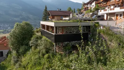 Am Hügel liegt ein verwilderter Garten, daneben steht ein haus