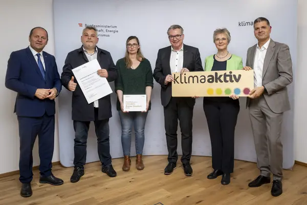 mehrere Personen mit Urkunde in der Hand schauen in die Kamera