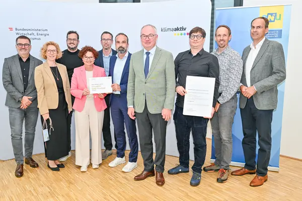 Personen mit Urkunde schauen in die Kamera