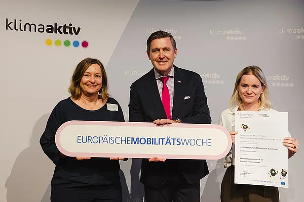 Menschen mit Urkunde und klimaaktiv Schild lächeln in die Kamera