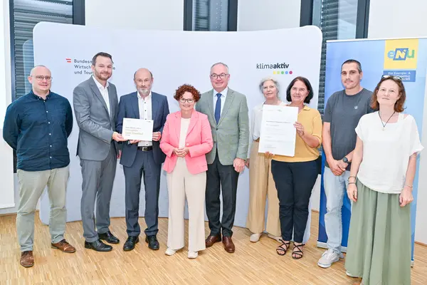 Personen mit Urkunde schauen in die Kamera