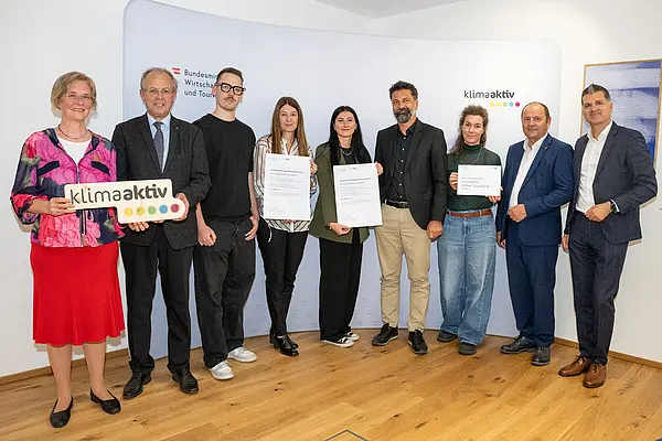 eine Gruppe von Menschen auf einer Bühne hält Urkunden in die Kamera