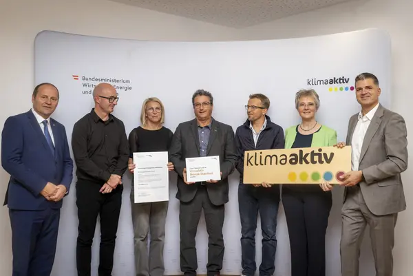 mehrere Personen mit Urkunde in der Hand schauen in die Kamera