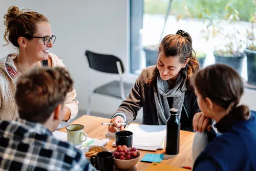 Vier junge Personen sitzen an einem Tisch und halten ein Meeting.