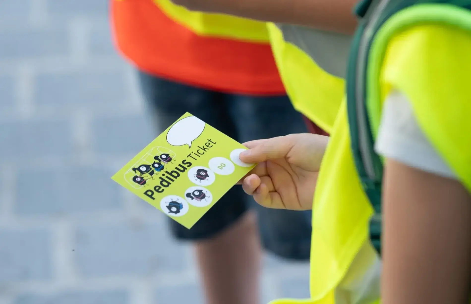 Kinderhand hält ein Pedibus-Ticket