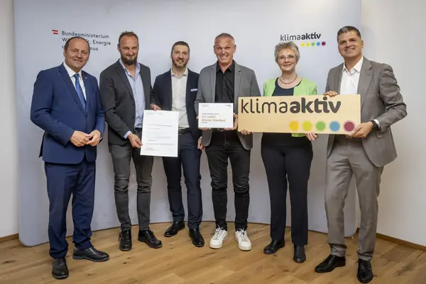 mehrere Personen mit Urkunde in der Hand schauen in die Kamera