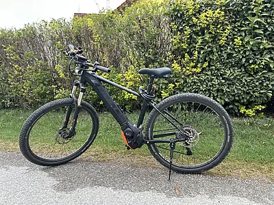 Elektrisches Fahrrad steht auf Schotterweg vor grünem Busch