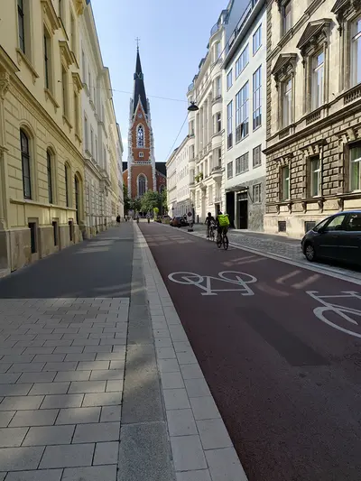Blick auf die neue rote asphaltierte Fahrradstraße in der Argentinierstraße, im Hintergrund die St. Elisabeth Kirche
