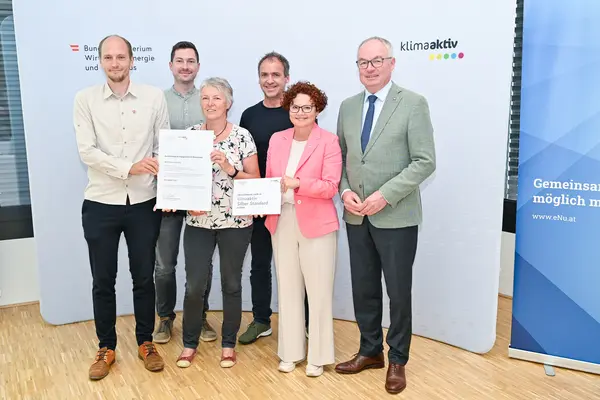 Personen mit Urkunde schauen in die Kamera