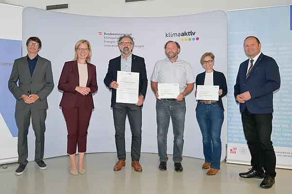 Im Bild: Klimaschutzministerin Leonore Gewessler, LHStv. Josef Geisler, DI Robert Taunmüller (Energie Tirol), Ing. Ferdinand Jenewein und DI (FH) Thomas Hackl (TIGEWOSI, TIROLER GEMEINNÜTZIGE WOHNUNGSBAU- UND SIEDLUNGS GES.M.B.H.), DI Christina Krimbacher