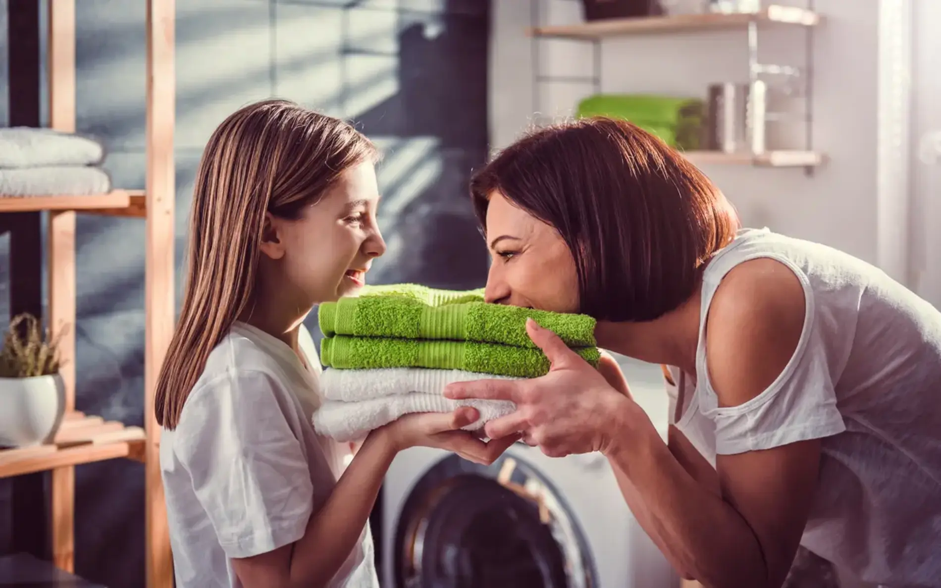 Eine Frau steht gegenüber ihrer Tochter. Beide riechen an den frischen Handtüchern.