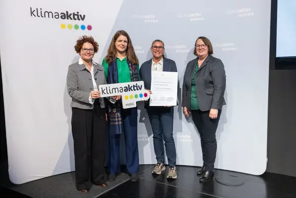 4 Personen mit Urkunde und klimaaktiv Schild schauen in die Kamera