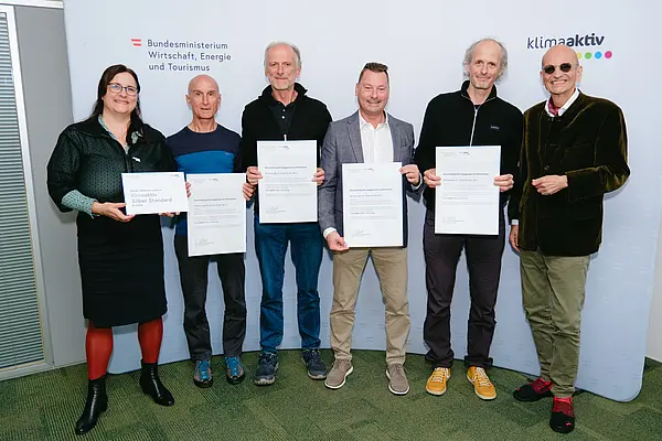 Personen mit Urkunden schauen in die Kamera