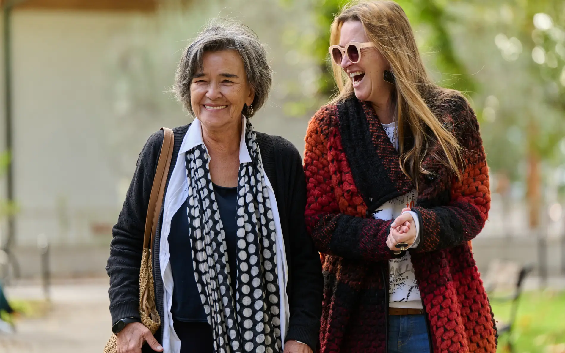 zwei ältere Frauen gehen nebeneinander und lachen 