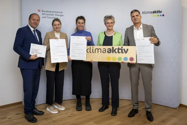 mehrere Personen mit Urkunde in der Hand schauen in die Kamera