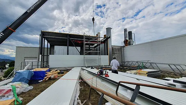 Außenaufnahme einer Baustelle mit Stahlkonstruktion und Bauarbeiten an einer industriellen Anlage unter wolkigem Himmel.