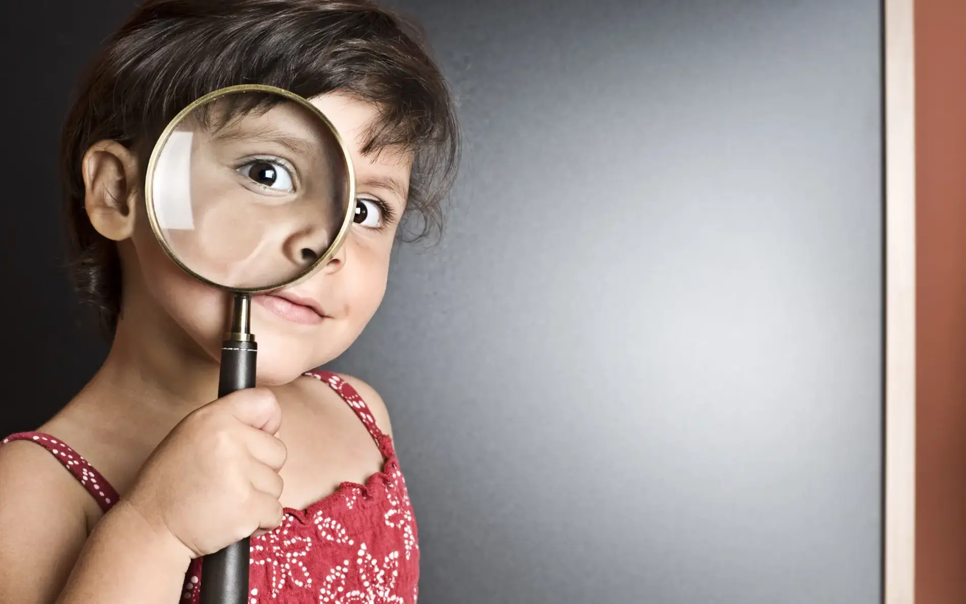 Ein Mädchen schaut durch eine große Lupe