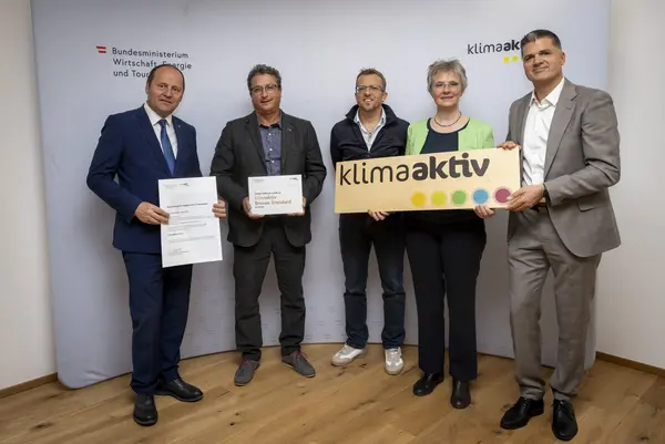 mehrere Personen mit Urkunde in der Hand schauen in die Kamera