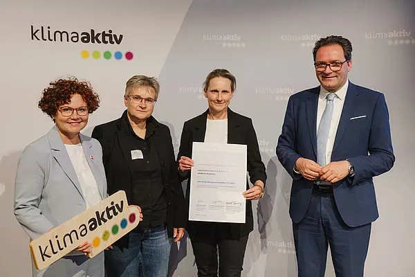 Menschen mit Urkunde und klimaaktiv Schild lächeln in die Kamera
