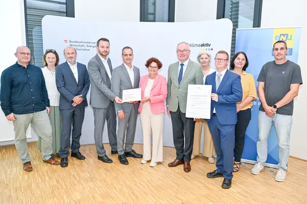 Personen mit Urkunde schauen in die Kamera