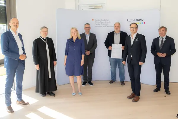 klimaaktiv Bronze Auszeichnung für die Planung der Wohnhausanlage "Gartenpark Korneuburg_BT1". Im Bild: Jürgen Schneider (Klimaschutzministerium), Barbara Finster, Christian Holler, Michael Schebesta (Wiener Komfortwohnungen Holding), Pfarrer Stefan Koller, Michael Haugeneder (ATP Sustain), Herbert Greisberger (enu)