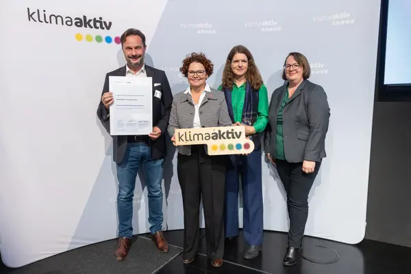 4 Personen mit Urkunde und klimaaktiv Schild schauen in die Kamera