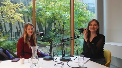 2 Frauen lächeln in die Kamera. Vor ihnen Mikrofone, hinter ihnen ein Garten.