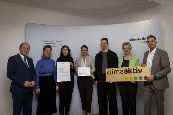 mehrere Personen mit Urkunde in der Hand schauen in die Kamera