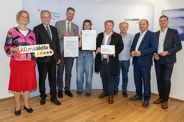 eine Gruppe von Menschen auf einer Bühne hält Urkunden in die Kamera