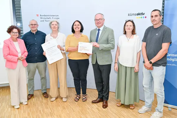 Personen mit Urkunde schauen in die Kamera