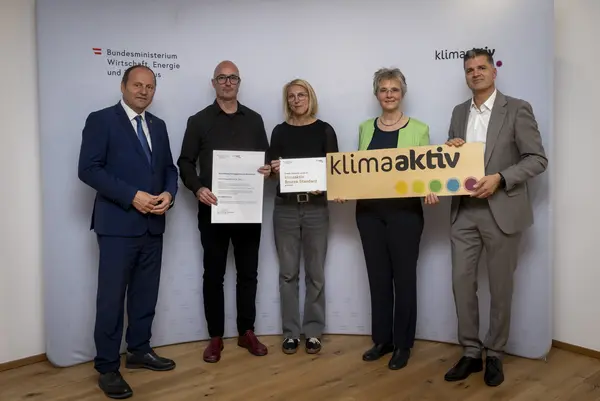 Menschen mit Urkunde schauen in eine Kamera