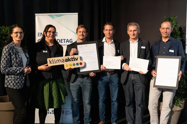 Personen mit Urkunden schauen in die Kamera