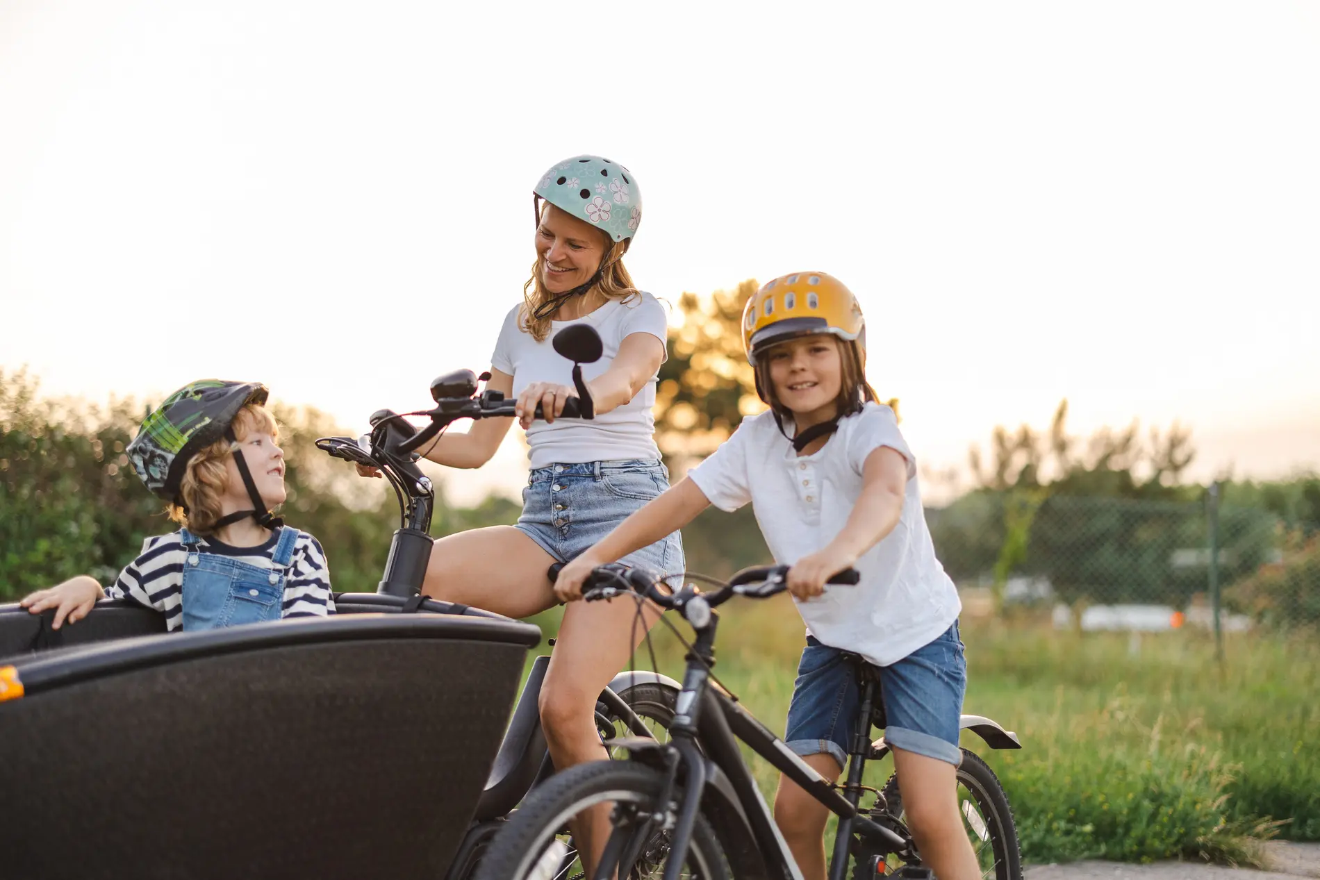 Eine Familie mit einem Transportrad. Das kleinere Kind sitzt im Transportrad, das größere auf einem eigenen Kinderfahrrad
