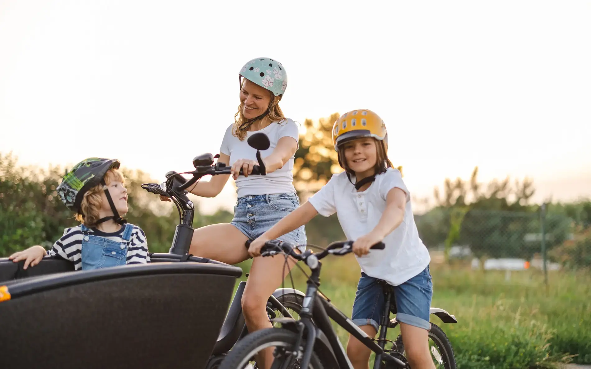 Eine Familie mit einem Transportrad. Das kleinere Kind sitzt im Transportrad, das größere auf einem eigenen Kinderfahrrad