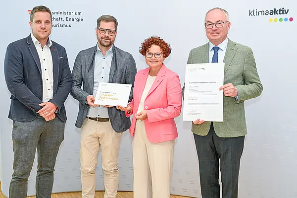 Personen mit Urkunde schauen in die Kamera