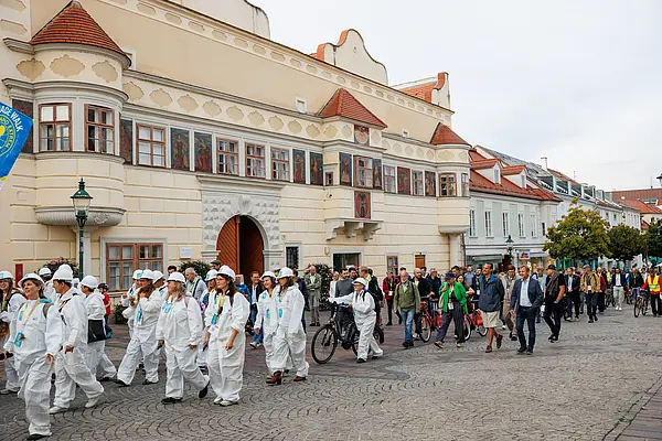 Eine Gruppe in weißen spacigen Outfits und eine Gruppe mir Rädern spazieren durch eine Fußgängerzone