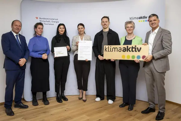 mehrere Personen mit Urkunde in der Hand schauen in die Kamera