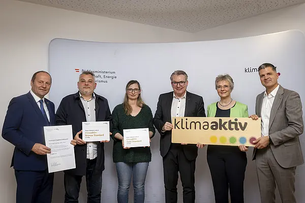 Menschen mit Urkunde schauen in eine Kamera