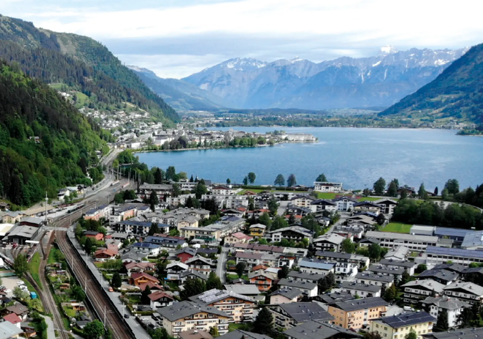 Titelbild für die Broschüre "Siedlungen und Quartiere". Zu sehen ist eine Gemeinde am See, umgeben von einem Bergpanorama