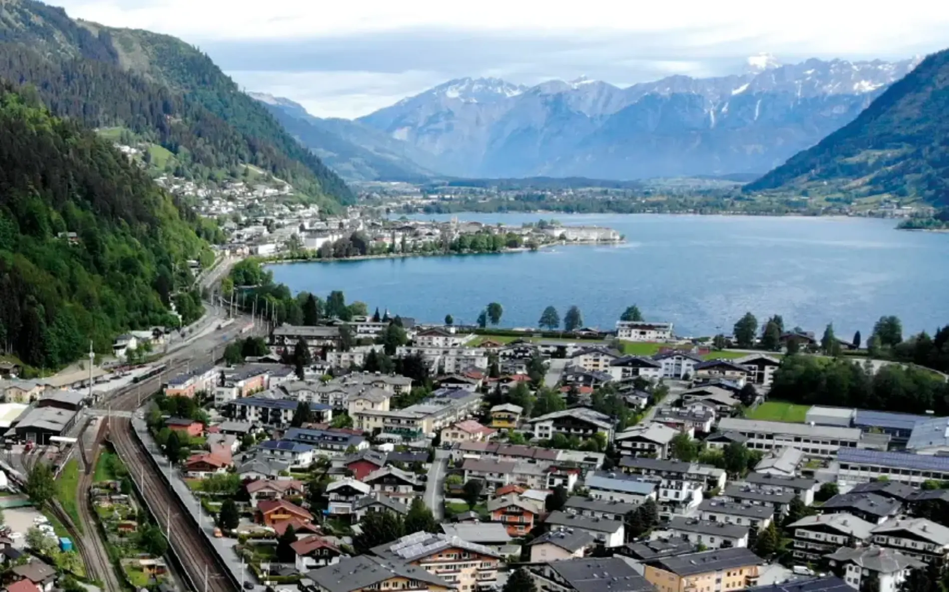 Titelbild für die Broschüre "Siedlungen und Quartiere". Zu sehen ist eine Gemeinde am See, umgeben von einem Bergpanorama