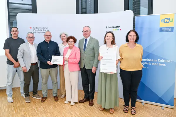 Personen mit Urkunde schauen in die Kamera